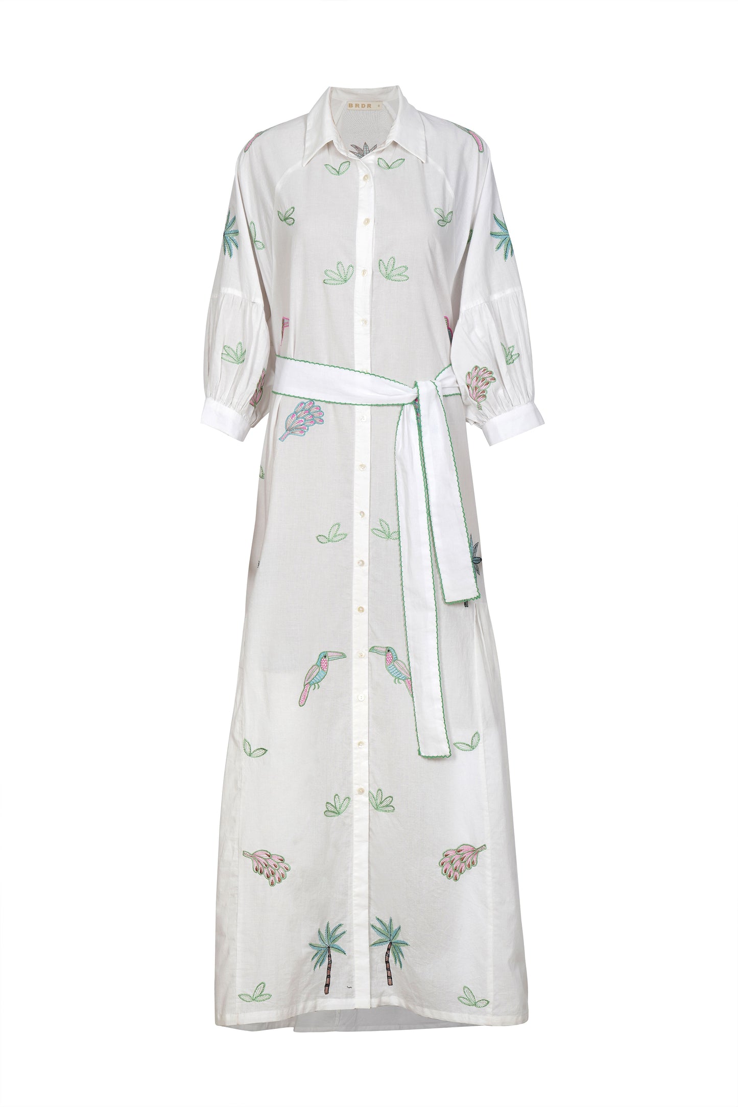 This gorgeous dress from BRDR is perfect for a summer occasion. A long maxi length shirt style dress in pure white with stunning multi coloured embroidery on the front and the sleeves. Gentle pleats at the side from below the waist add a little fullness to the skirt. The full bracelet length sleeve has slight gathers and a cuff with single button. There is a white cotton fabric belt with blanket stitching in bright green to finish. The dress is very light so comes with a short slip in cotton.