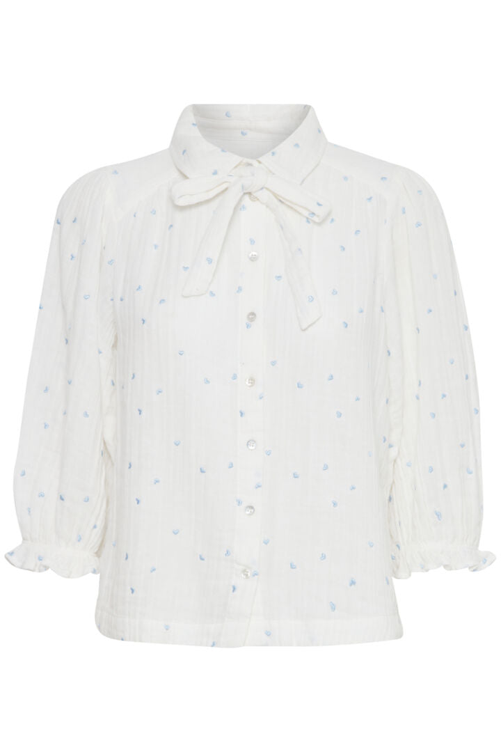 The cutest most feminine piece from Atelier Reve. This stunning shirt style blouse in the softest of fabrics has a small collar and a button front . The tie at the neck is detachable with a simple button fastener at the back of the neck under the collar. The sleeves are puffed and full and are bracelet length with a delicate elasticated cuff. Embroidered with tiny pretty blue hearts throughout this is an exceptionally pretty piece.