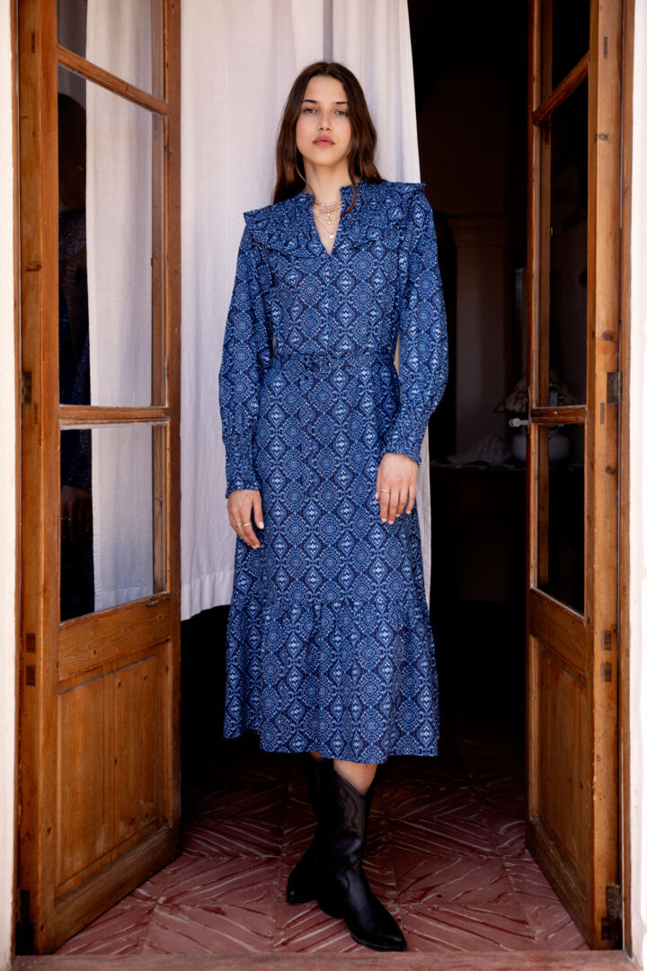 A stunning dress by Scandi brand Atelier Reve. This stunning blue piece is in a fabulous Ikat print. It's longer length makes it perfect with boots but also with trainers in Spring/Summer. The notch neck is beautifully detailed with frills and shirring. The long sleeves have a long shirred cuff . There are five fabric covered buttons from the top of the V to the waist and there is a belt with fabric covered buckle. Frill at the hem.