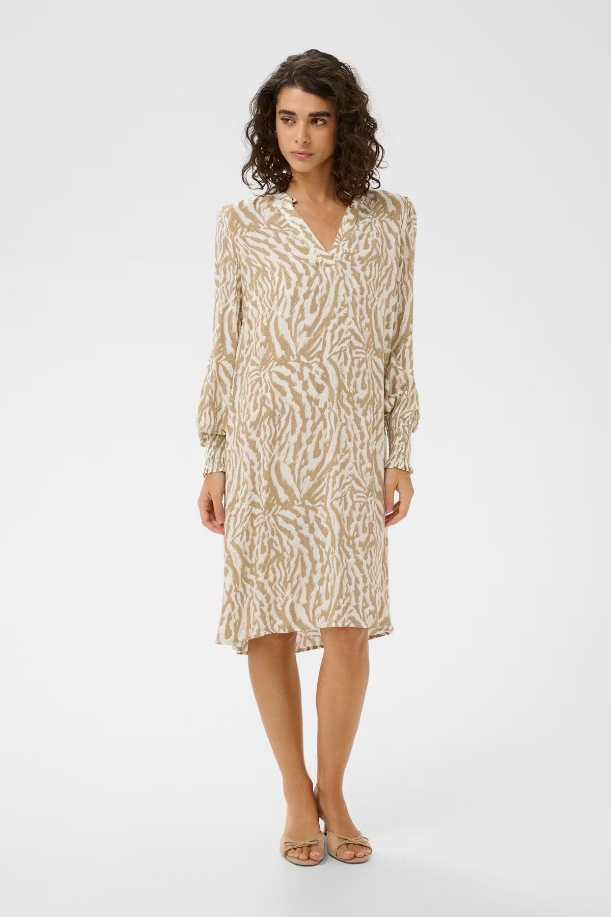 This neutral print shorter dress from KAFFE features a straight silhouette, V-neckline with subtle ruffle trim, and long voluminous sleeves with wide, gathered cuffs for easy elegance. The fit is true to size .
