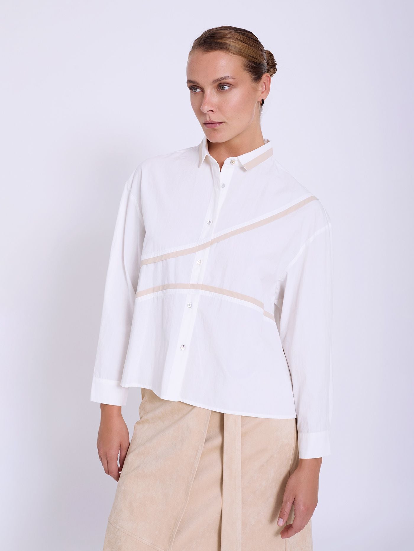 A super chic piece from Scandi brand SKATIE in the crispest of cottons. Super fresh and a bit of a statement piece, A boxy shirt with a small collar trimmed with a neutral beige. The long sleeves have a single button to fasten. The blouse is slightly A line in shape and has two flashes of beige across the front. The fit is neat.