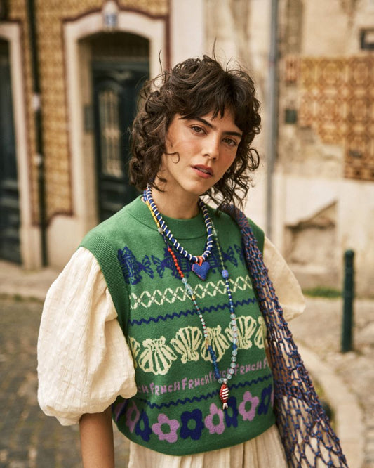 Sleeveless sweater from Parisian brand FRNCH with multicolored jacquard patterns on a green base. A striking piece perfect for now layered over a shirt. The fit is true to size.