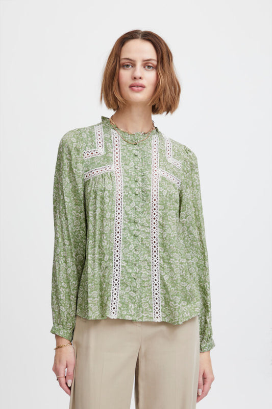 Another beautiful piece from Scandi brand Atelier Reve in a stunning pale green and off white floral print. A round neck with a delicate frill . this blouse fastens with fabric covered buttons from the neck to the hem. The long sleeves have a single button cuff. There are lace ribbon panels to the front and across the top of the back of the blouse. A great transitional piece going into Spring.