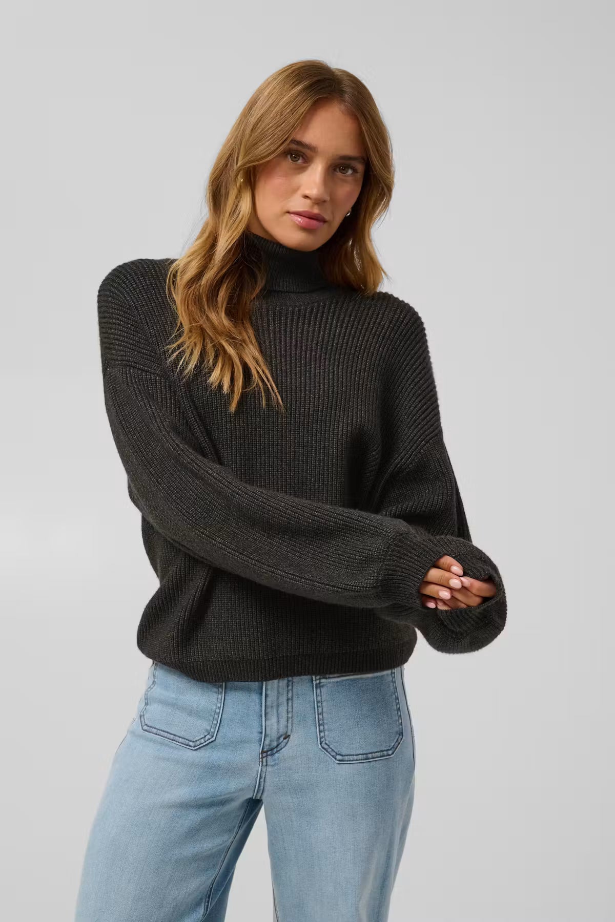 This polo neck sweater from KAFFE features a loose, boxy silhouette with dropped shoulders and slightly ballooned long sleeves. The ribbed knit texture adds structure, while the straight hem falls below the waist for a contemporary fit.