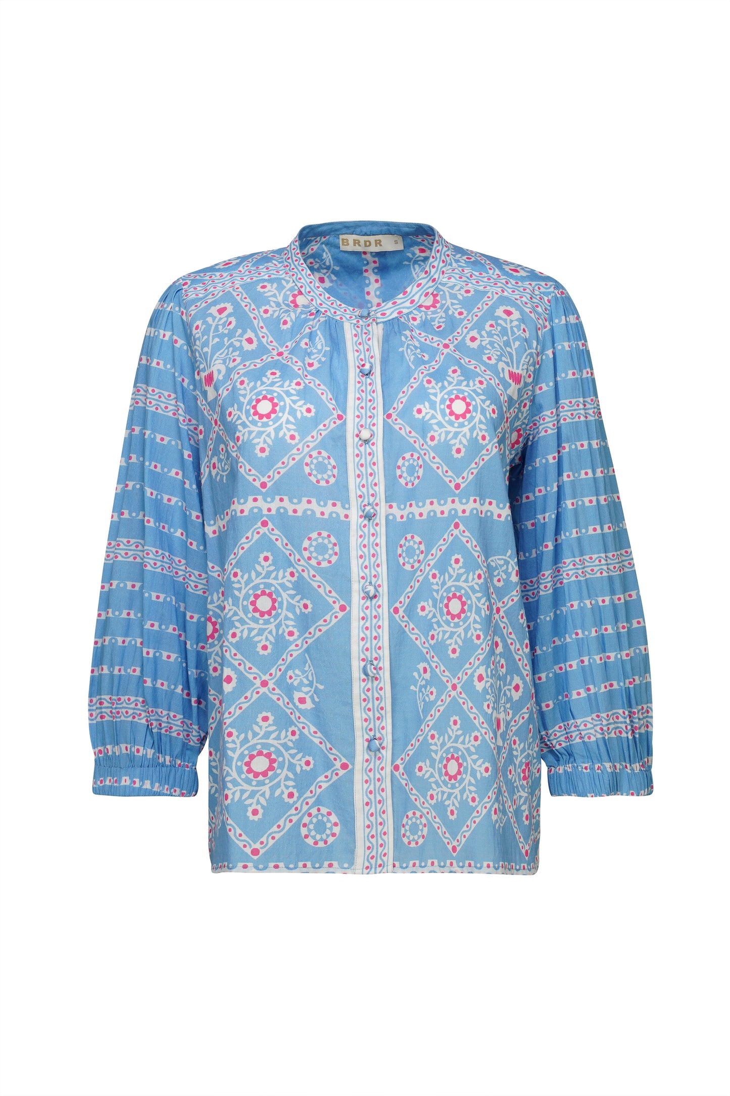 A beautiful blouse from our newest brand BRDR in a striking Summer print. In a pretty Summer blue with accents of white and pint this collarless blouse is a winner. Wear with washed denim for everyday or jazz up for a Summer party with a white trouser or skirt. There are fabric covered buttons from the neck to hem and the three quarter length sleeves are gently gathered with and elasticated cuff. A simply stunning piece.