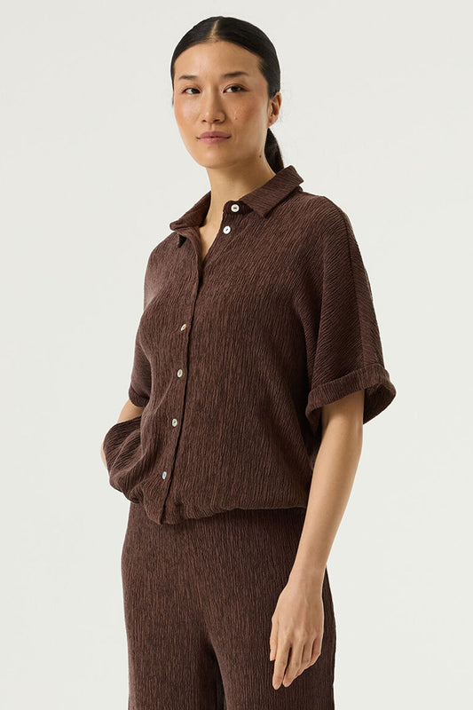 Textured fabric blouse in earth brown from GARCIA. With a collar and button front this very wearable piece is a wardrobe staple. The contrast buttons at the front are finished at the hem with a tie to gather. The sleeves are capped with a small turnup and the fit true to si