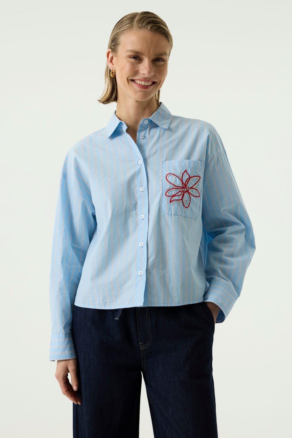 The Breeze Shirt from GARCIA is a stylish boxy-fit shirt featuring delicate contrast-coloured stripes for a fresh, contemporary look. It has a single breast pocket beautifully finished with delicate flower and bead embroidery, adding a feminine touch. The long sleeves feature smart single-button cuffs, making this an effortlessly stylish piece that looks great worn casually or dressed up.