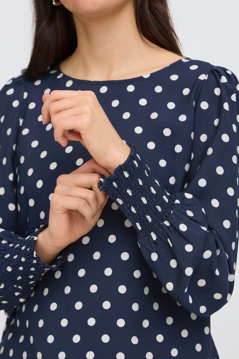 This women's blouse from FRANSA features a relaxed fit, elegant round neckline, and long sleeves with gathered cuffs. Intricate design detailing at the edges adds refined style, making it versatile for both casual and smart occasions.