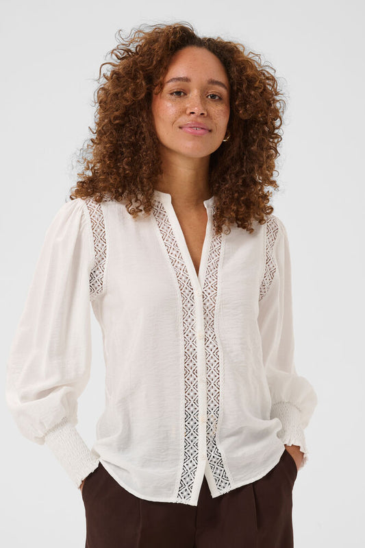 The Kaffe KAdelia Shirt in chalk is a chic and versatile piece designed with a soft woven finish and elegant long sleeves. Featuring a modern band-style collar, this shirt offers a clean and contemporary silhouette, while open embroidered detailing on the front and along the sleeve seams adds a delicate, feminine touch. Perfect for effortless everyday styling or dressing up for a polished look.
