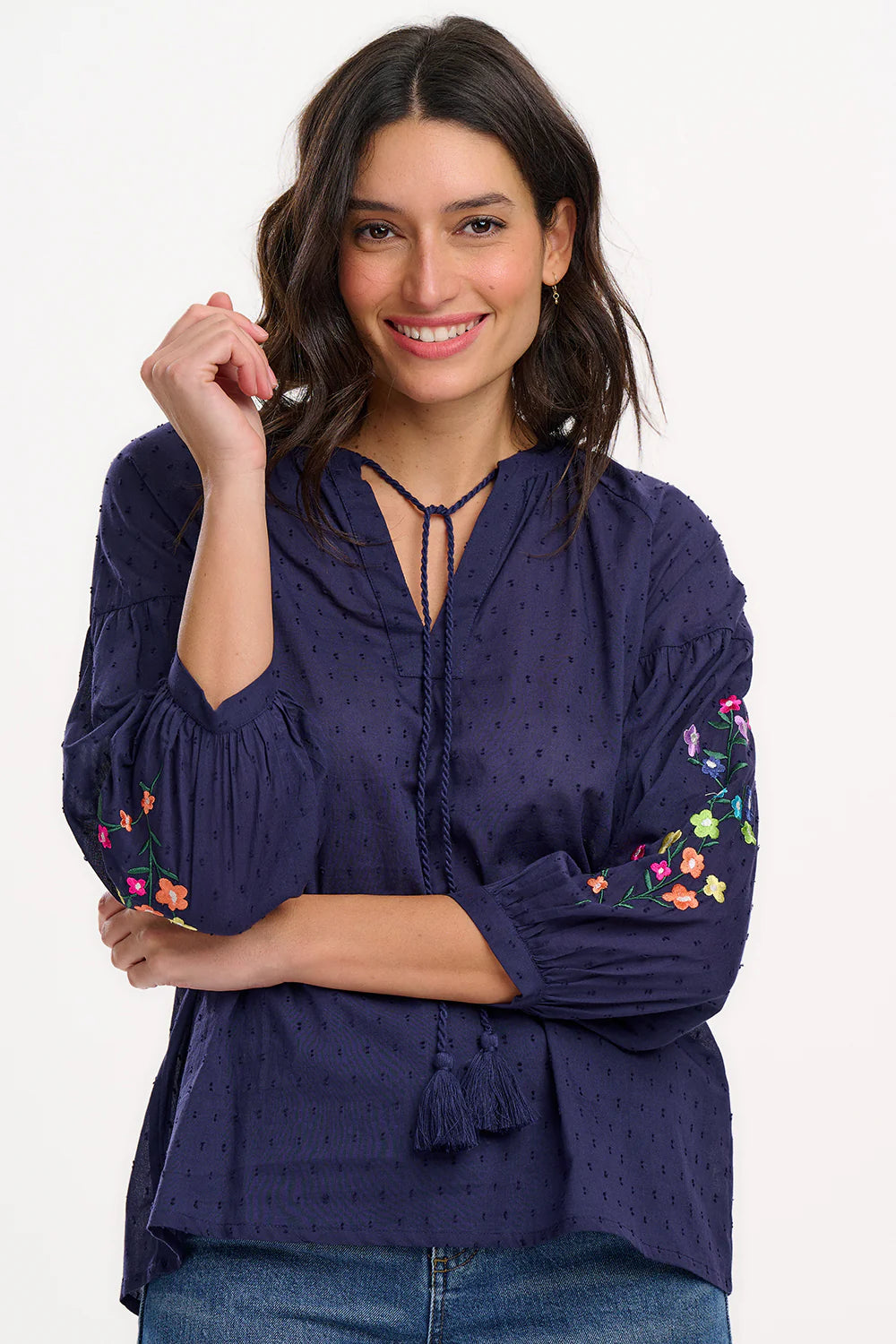 The Delphi from SUGARHILL takes inspiration from the boho designs of the 70's. With a gathered collared deep V-neck and tassel ties. Creating a classic Boho shape with fun 3/4 length sleeves, gathered from the dropped shoulder seam. Featuring delicate embroidered flowers on the sleeves, on a navy dobby spot cotton.