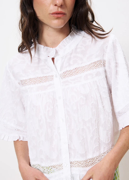 The FRNCH Einat Shirt in Creme, a short-cut, casual, short sleeved, pretty bohemian blouse with a ruffle collar and lace inset detail. Buttons to the front and the fit is short and boxy and neat in size.