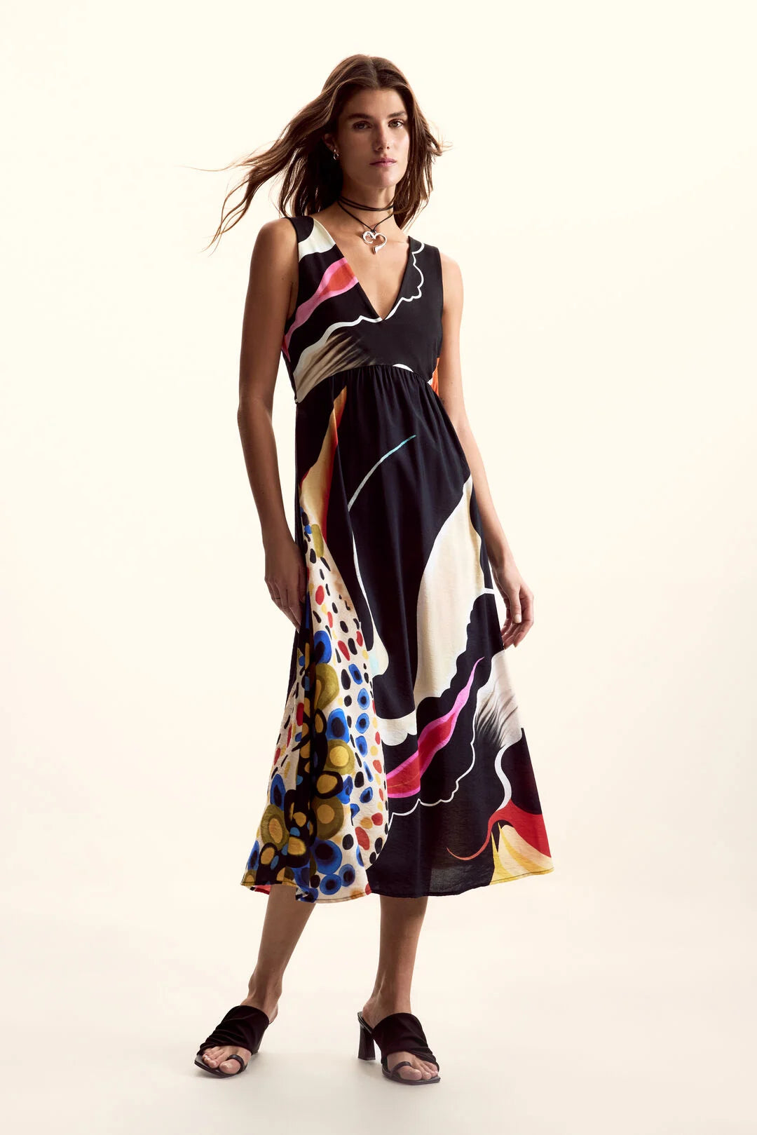Sleeveless dress in a flowing fabric with an arty print in various colors. V-neck and midi length. Design by M. C. Lacroix for Spanish brand DESIGUAL.