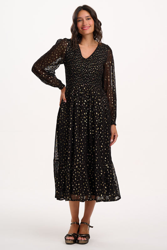 Turn heads this season in the Jacqueline Shirred Midi Dress from SUGARHILL . Adorned with shimmering golden spots filled with jewel-toned colours on a classic black base, this woven beauty delivers sparkle without the fuss. The flattering shirred bodice, sheer long sleeves, and flowy tiered skirt create an effortlessly elegant silhouette. Perfect for parties or any occasion.