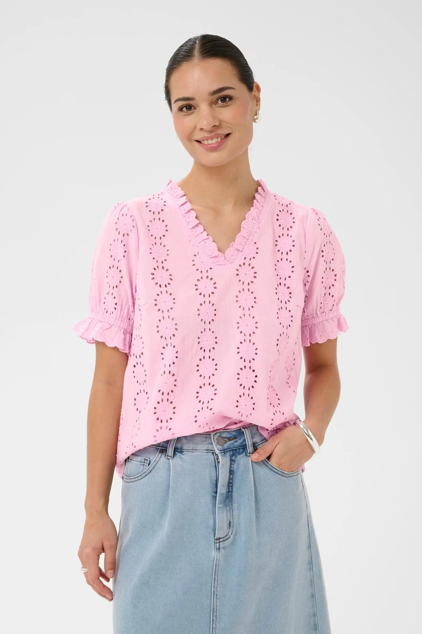 Short-sleeved blouse from KAFFE with a straight fit, featuring vertical rows of openwork eyelet embroidery throughout. Designed with a V-neckline edged in ruffles and finished with ruffled sleeve hems. The surface has a soft, matte appearance.The fit is true to size.