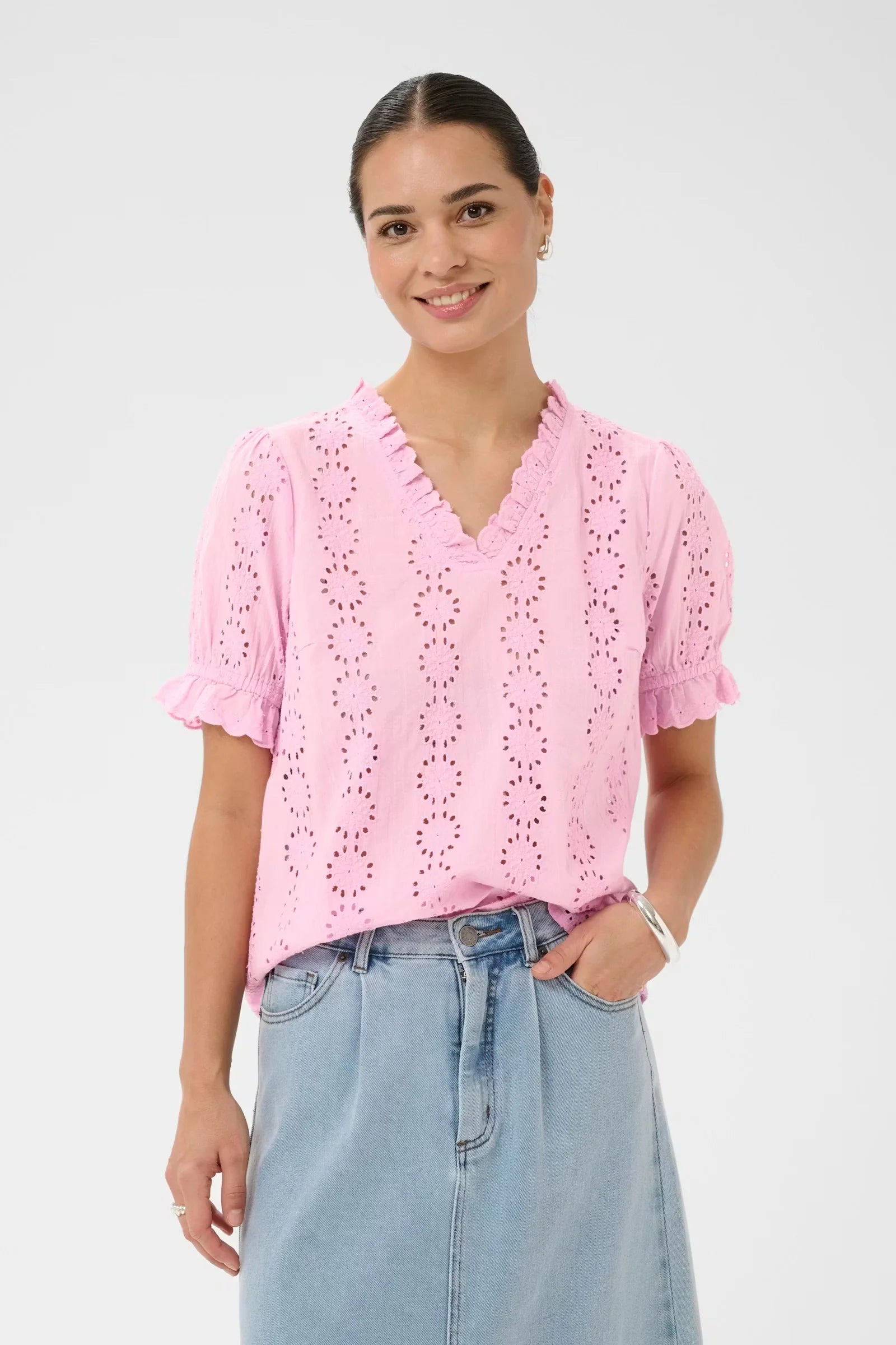 Short-sleeved blouse from KAFFE with a straight fit, featuring vertical rows of openwork eyelet embroidery throughout. Designed with a V-neckline edged in ruffles and finished with ruffled sleeve hems. The surface has a soft, matte appearance.The fit is true to size.