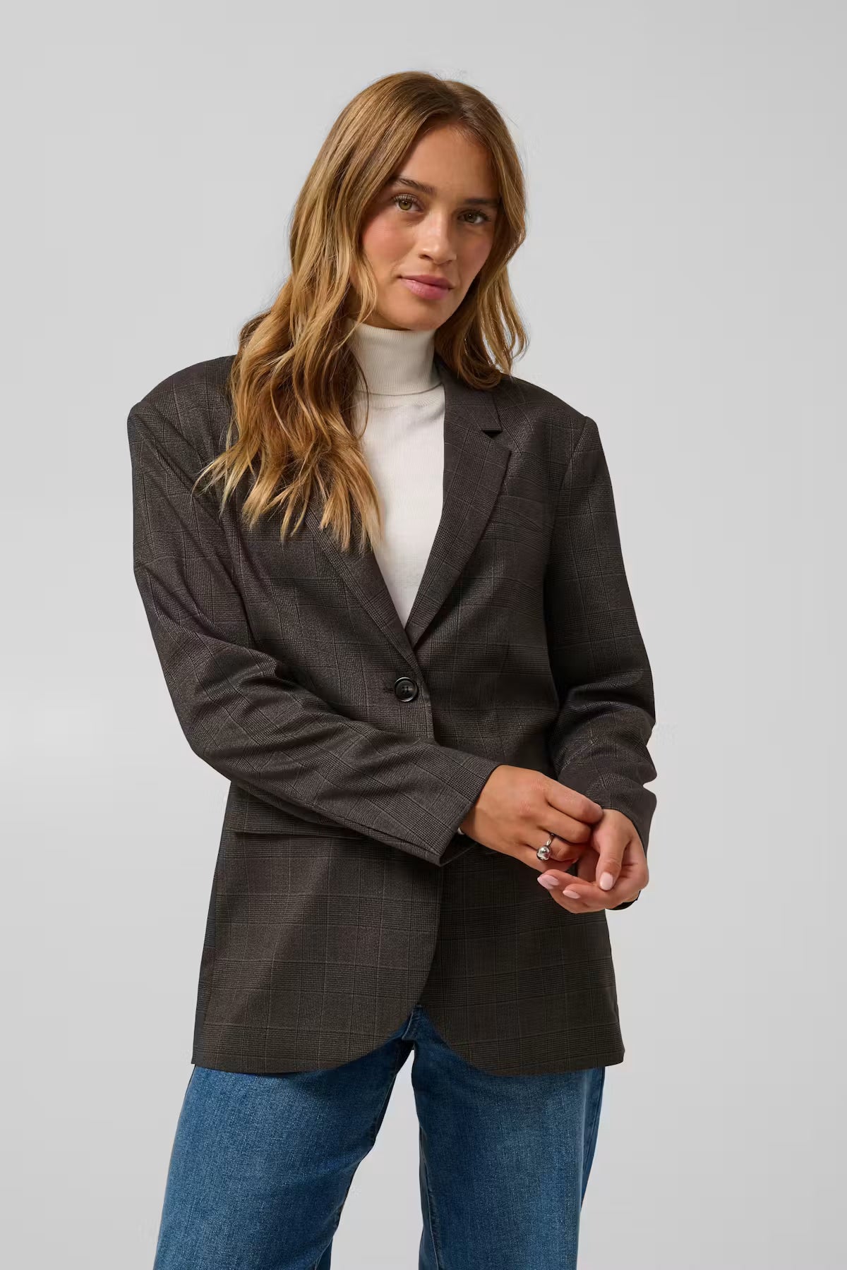 This blazer from KAFFE features a straight, regular-fit silhouette with a classic notched lapel neckline and long sleeves. The design is enhanced with a two-button front closure, flap pockets, a single chest welt pocket, and visible check-patterned surface detailing throughout.