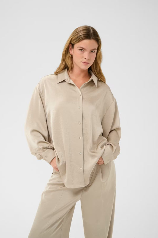 Button-up shirt from Scandi brand KAFFE with a subtle sheen, featuring a classic collar, full-length sleeves, and a curved hem. The relaxed fit adds an effortless, modern edge while the smooth surface delivers a clean, polished look for any wardrobe.