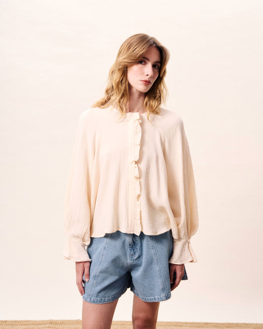 A beautiful ecru cotton blouse from FRNCH with pleated details and romantic ruffles. Collarless and loose fitting with a statement pleated back. The button front is concealed under a hidden placket. Long sleeves are pleated and have an elasticated cuff with a single button. The fit is true to size and the fabric is 100% cotton.