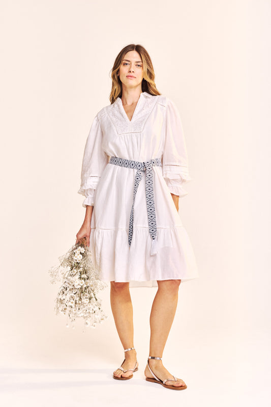 A beautiful truly Summer dress from One Collective in a crisp white fabric. The flattering notch neck is trimmed with broderie anglais and there is a smart shirt style collar The three quarter sleeve is gathered and slightly elasticated and has 2 pin tucks. It finishes below the knee with a single tier and there ia a navy and white Aztec style printed belt at the waist . The fit is true to size.