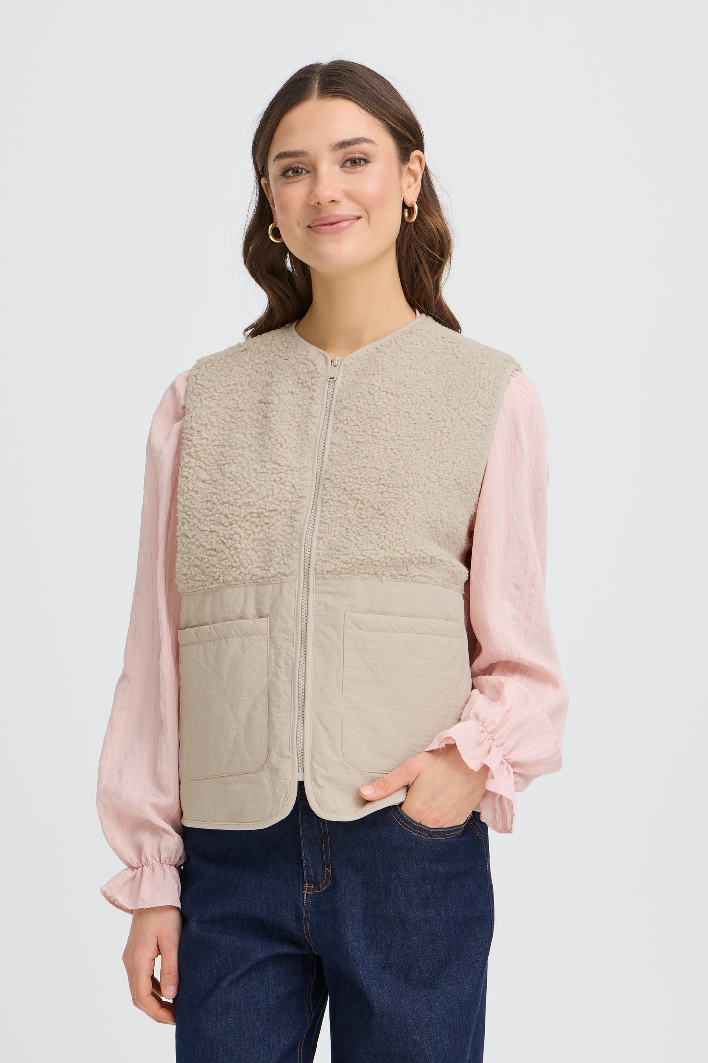 The FRANSA Mikala Waistcoat is a versatile layering essential designed for spring styling. This relaxed-fit vest features a convenient zip closure, making it effortless to adjust throughout the day. The sophisticated neutral hue pairs seamlessly with sweaters, blouses, and lightweight knitwear, offering endless outfit combinations. Whether you're layering for warmth or adding visual interest to your look, this waistcoat delivers both comfort and contemporary style