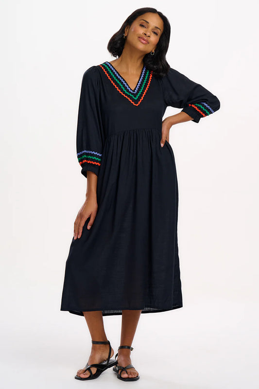 The Miquita dress from SUGARHILL is cut with a narrow shoulder and 3/4 length blouson sleeves, With a v-neckline, gathered loose smock skirt and lightweight Viscose fabric, it's designed for hot-weather comfort. Featuring Ric Rac detailing in blue, green and orange around the neckline and sleeve cuffs.