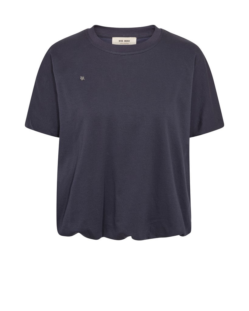 A modern T-shirt designed by MOS MOSH in a relaxed silhouette with a flattering balloon-shaped hem that creates soft volume and a contemporary look. Crafted from soft cotton, it features a classic O-neck and short sleeves, making it an easy everyday essential with a refined twist. Style it with jeans, tailored trousers, or skirts for effortless versatility.