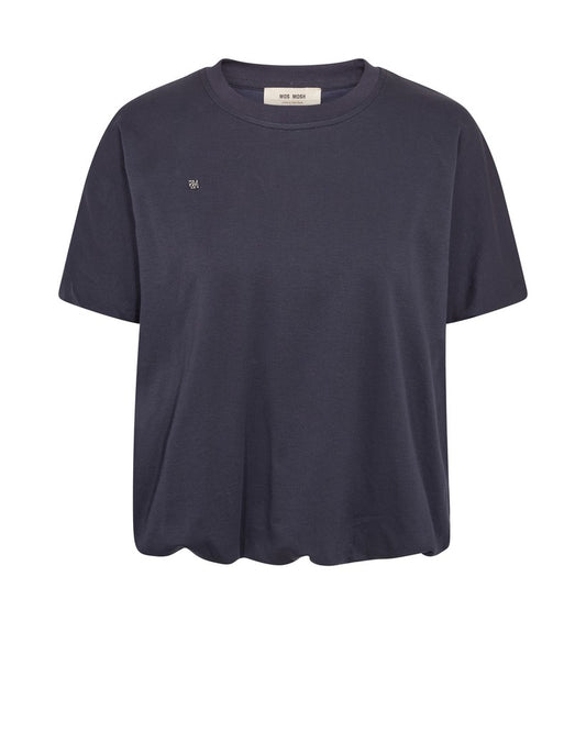 A modern T-shirt designed by MOS MOSH in a relaxed silhouette with a flattering balloon-shaped hem that creates soft volume and a contemporary look. Crafted from soft cotton, it features a classic O-neck and short sleeves, making it an easy everyday essential with a refined twist. Style it with jeans, tailored trousers, or skirts for effortless versatility.