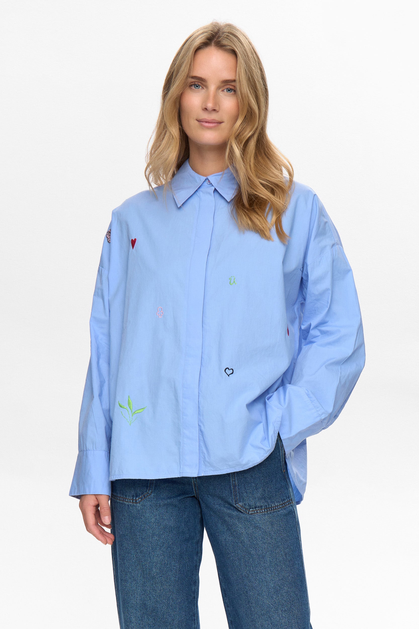 A classic but very oversized shirt with a standard collar and button front from NUMPH. Long sleeves with a wide cuff with two buttons to allow a different fit . The cuff is lined in a striped fabric so can be worn turned back. There are embroidered embellishments on the front and the words "To forever ever land" embroidered at the hem. The fit is very oversized.