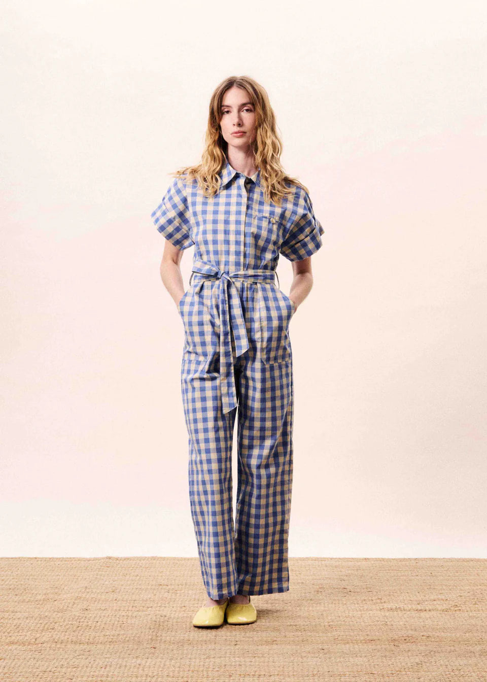 Cotton gingham check jumpsuit from FRNCH with tie belt. With a classic shirt style collar and button fastening this piece is easy to wear . There is a single breast pocket and concealed buttons. The cap sleeves are at a flattering length with a turn up. There are patch pockets at the front.