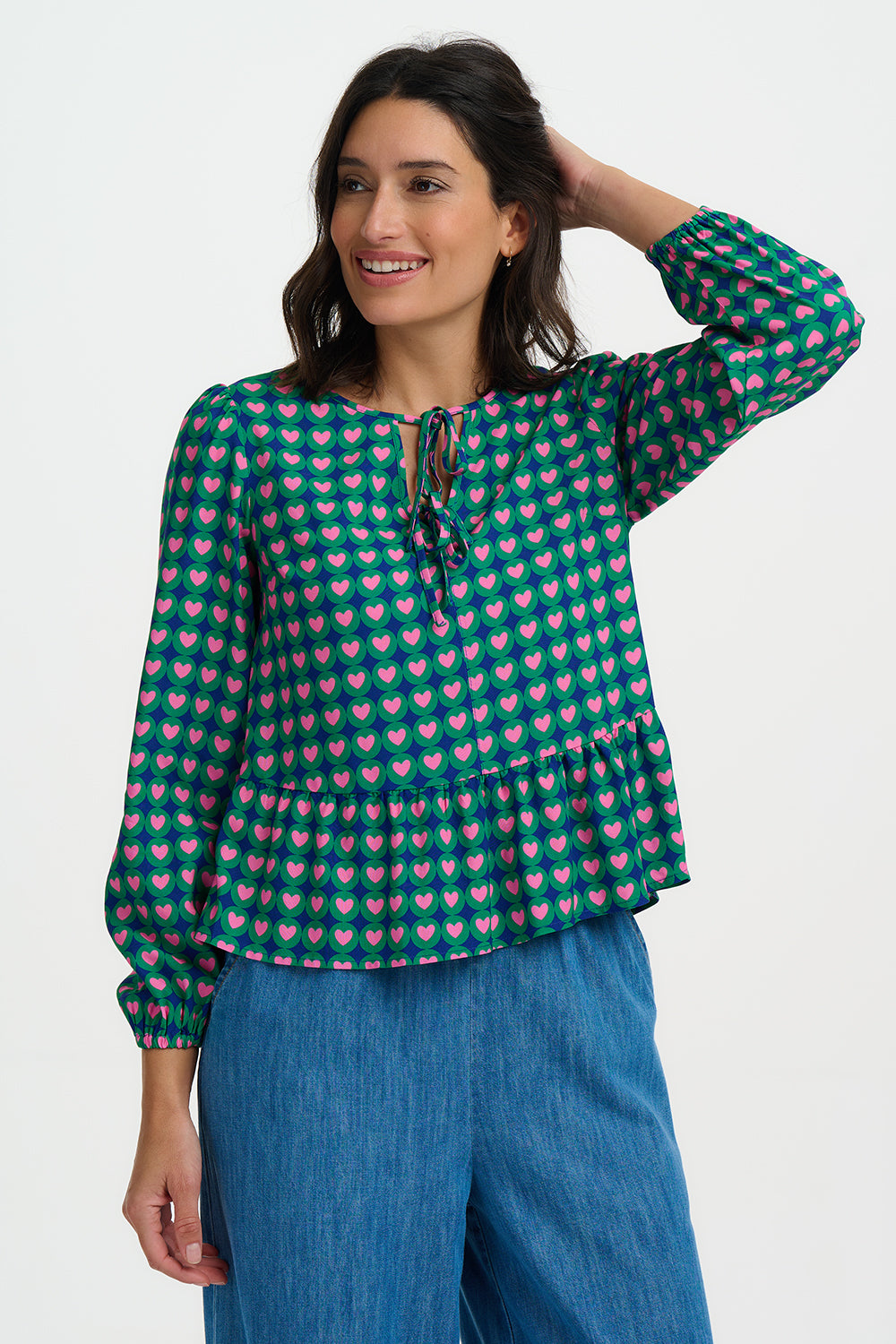 The Olina Top is a playful, easy-to-wear style from SUGARHILL with a relaxed silhouette and feminine details. Featuring a soft tie neckline, gentle gathers at the waist and blouson sleeves with elasticated cuffs, it’s finished in a bold retro heart print. Perfect for pairing with jeans or tailoring for effortless everyday charm.