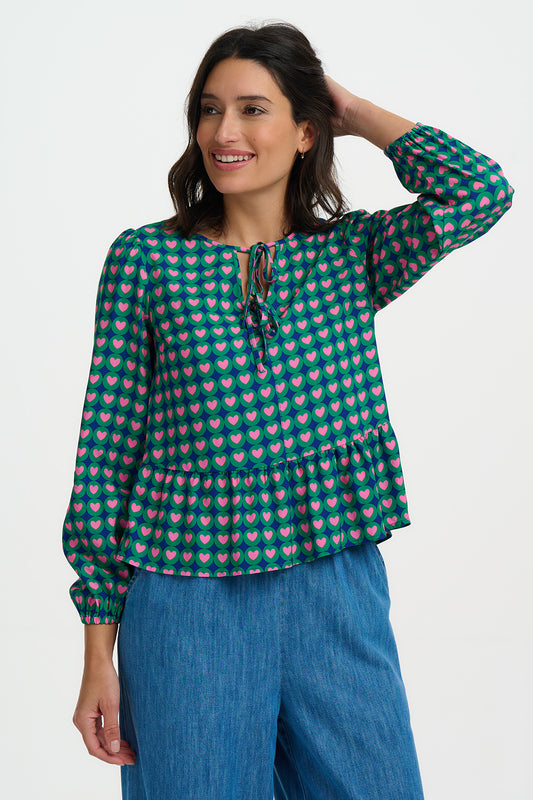 The Olina Top is a playful, easy-to-wear style from SUGARHILL with a relaxed silhouette and feminine details. Featuring a soft tie neckline, gentle gathers at the waist and blouson sleeves with elasticated cuffs, it’s finished in a bold retro heart print. Perfect for pairing with jeans or tailoring for effortless everyday charm.
