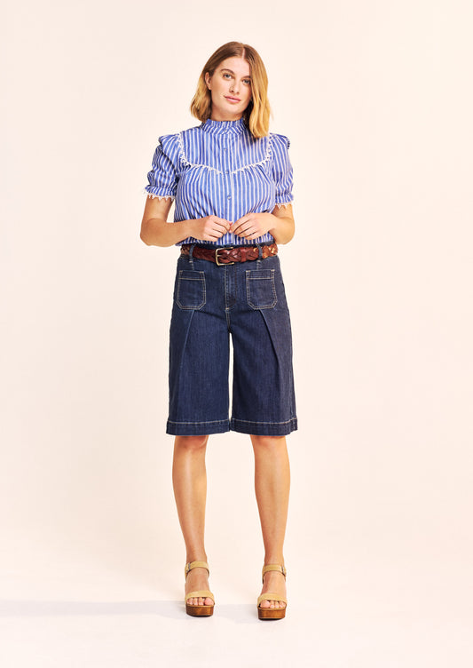 This beautiful piece by our new British brand ONE COLLECTIVE is in a classic blue with white stripes. As with every piece from this brand the attention to detail is exceptional. The A shaped blouse has a frill at the neck and a gathered bib front and back trimmed with a crisp white lace detailing. The slightly puffed short sleeves are gathered and again trimmed with a cotton lace. The fabric covered buttons add another dimension. The fit is true to size.