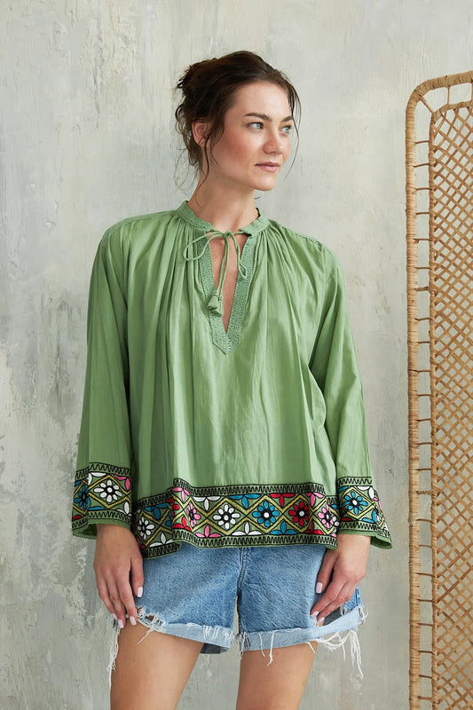 A beautifully cool Summer top from French brand Chico Soleil. A boho style piece with a collarless V neck with embroidered trim and tie at the neck. The long sleeves are the perfect cover for a hot holiday and the wide embroidered cuff super stylish and striking. The straight hem is also trimmed with the same broad embroidery. The fit is generous
