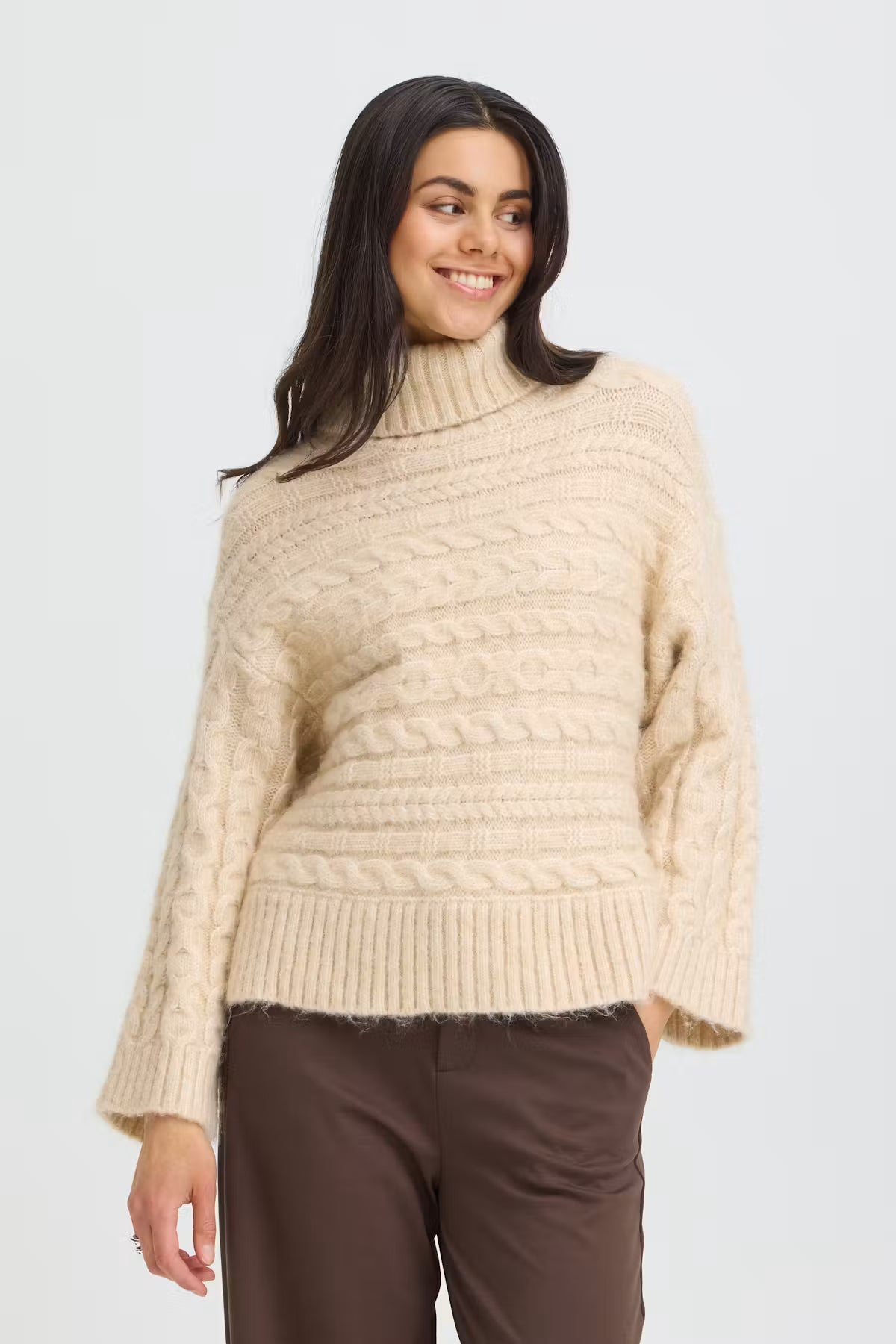 Cable knit turtleneck sweater from FRANSA features a soft finish and straight, boxy silhouette. Dropped shoulders and long wide sleeves add a modern touch. Distinct ribbed collar, hem, and cuffs complete the understated statement look.