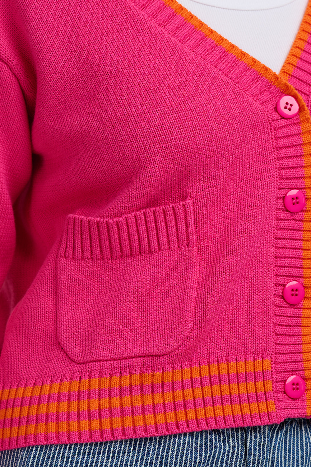 This vibrant V-neck cardigan from Sugarhill Brighton is crafted from 100% cotton for a soft, breathable feel that’s perfect for everyday layering. Designed in a bold pink hue with contrasting stripe details along the neckline, hem and cuffs, it brings a playful pop of colour to any outfit. Finished with a button-through front and practical patch pockets, it’s an easy-to-wear knit that works just as well over dresses as it does with jeans and tees.