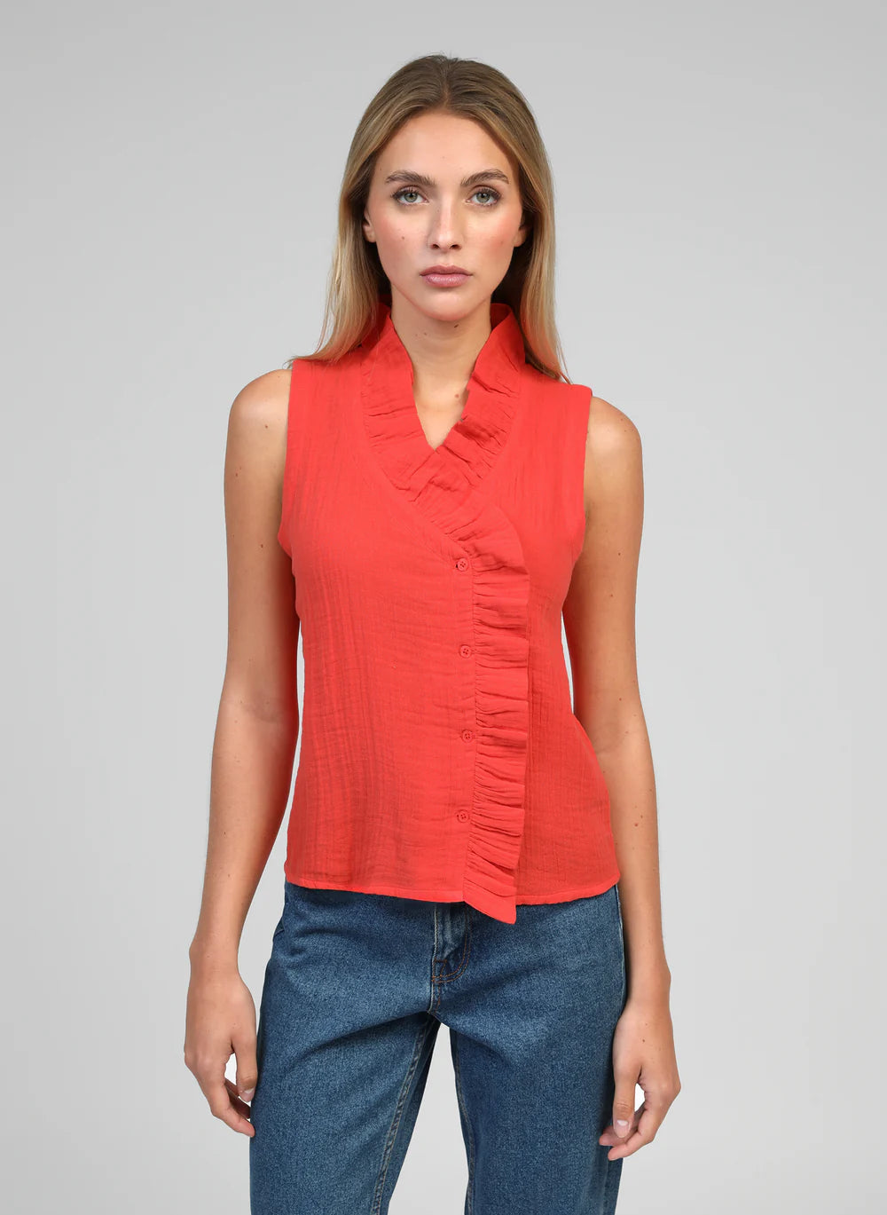 The Siloe Blouse by An'ge is a beautifully feminine piece with thoughtful design details. Featuring a delicate frill that frames the neckline and continues down the front, this sleeveless blouse is finished with an elegant off-centre button fastening for a contemporary twist.