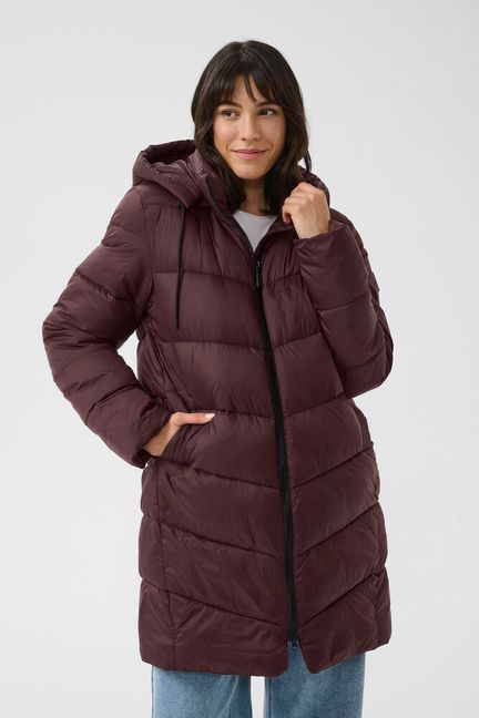 A long puffer jacket from KAFFE with a sleek, matte finish, featuring horizontal and diagonal quilting, a full-length front zipper, practical side pockets, and an adjustable drawstring hood for reliable coverage and relaxed comfort.