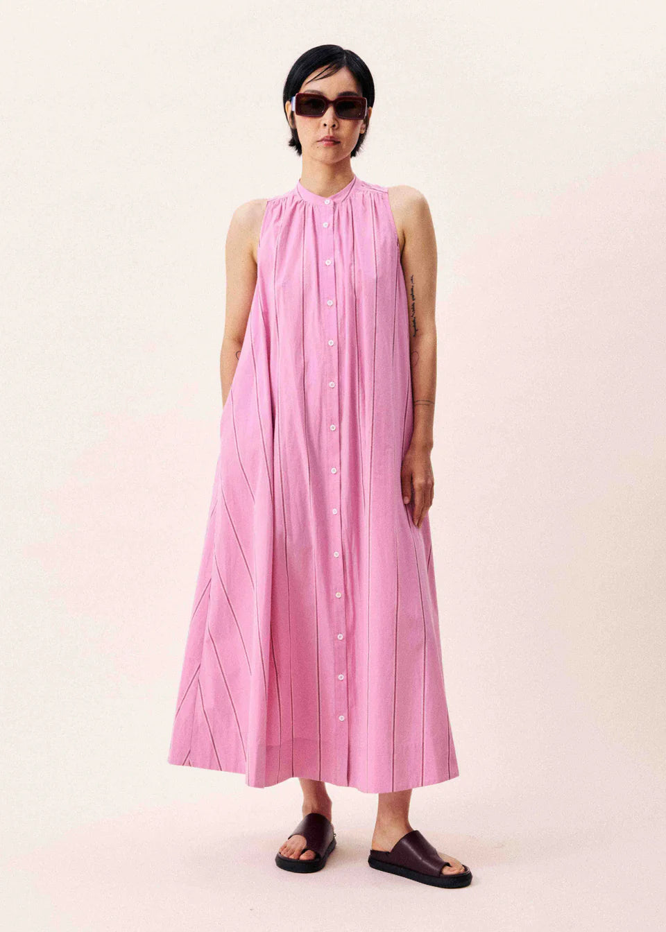 Long, sleeveless dress from FRNCH with central button fastening in pastel pink with a cool stripe. Maxi length with a round collarless neckline. Ankle length with fullness and seam pockets. Generous in fit.