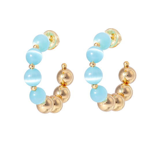 Our Tokyo earring from British brand Talis Chains is a fantastic way to add to some colour to your jewellery. These lightweight hoops mixes cat eye and gold plated beads making them easy to style with gold chain necklaces.
