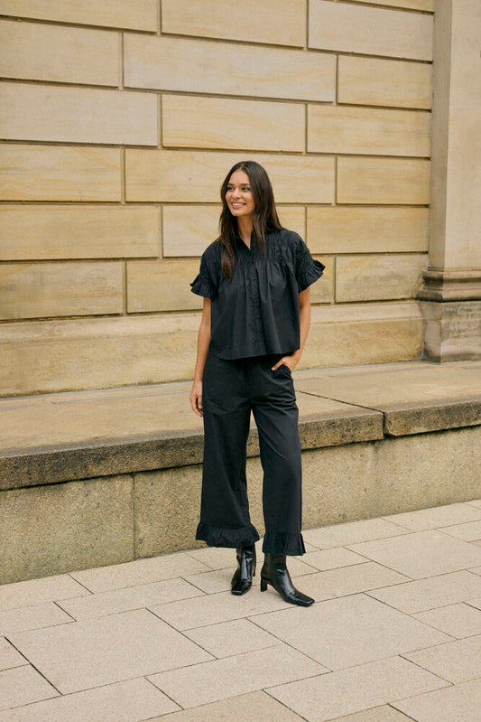 The Kaffe Verdina Flounce Shirt brings feminine elegance to everyday dressing. Crafted from 100% cotton, this relaxed-fit shirt features delicate gathered detailing across the front and statement flounce sleeves for added texture and movement. Finished with a classic collar and button-through front, it's an effortless piece for both smart and casual styling.