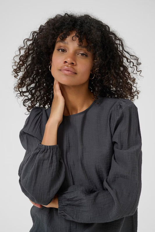 This women's blouse from Scandi brand KAFFE features a relaxed fit, round neckline, and long sleeves, offering everyday comfort and versatility. Subtle texture and gathered cuffs add understated design details to elevate any outfit.